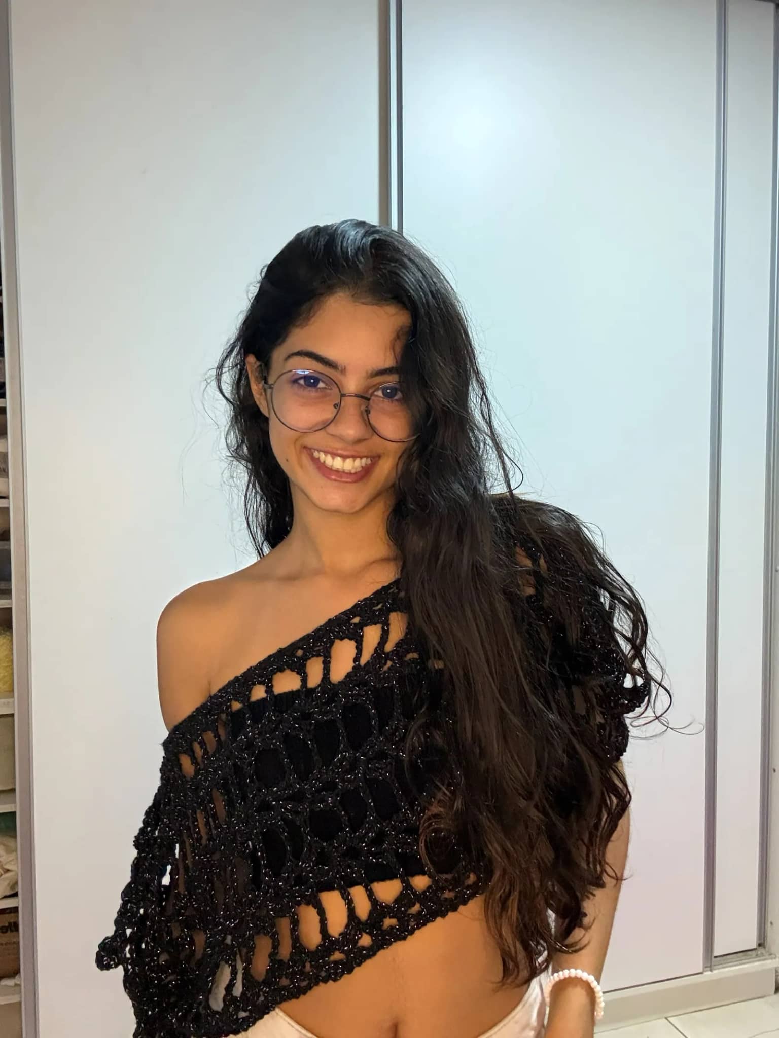 Bata de crochê preta de trama aberta, usada em um ombro só