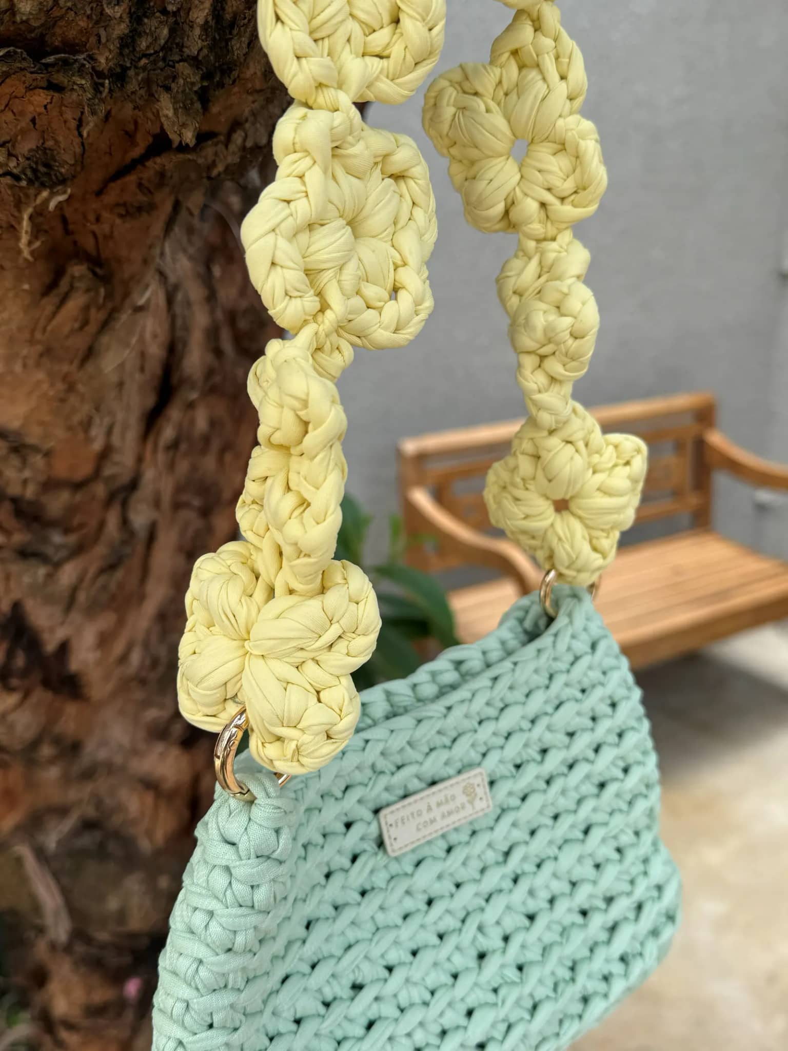Detalhe da alça de florzinhas amarelas presa à bolsa por argola dourada