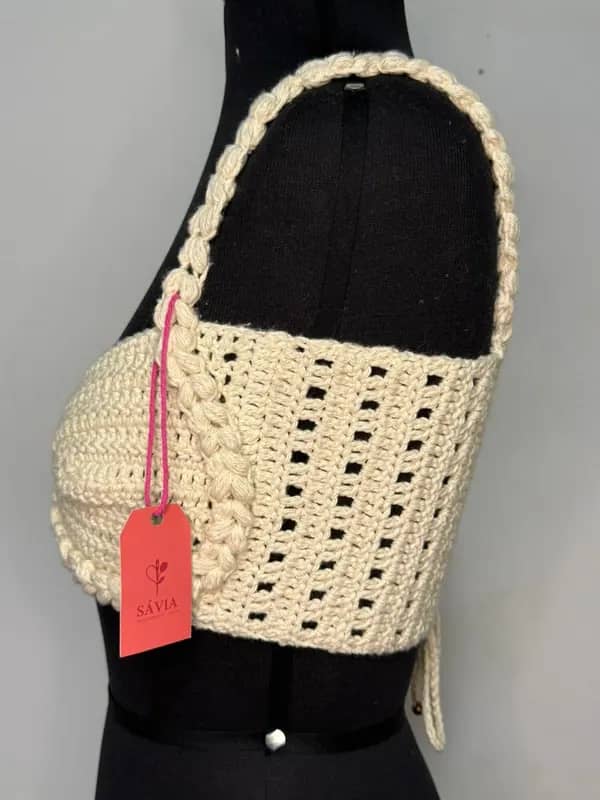 Bralette de crochê creme visto de lado, com etiqueta da Sávia