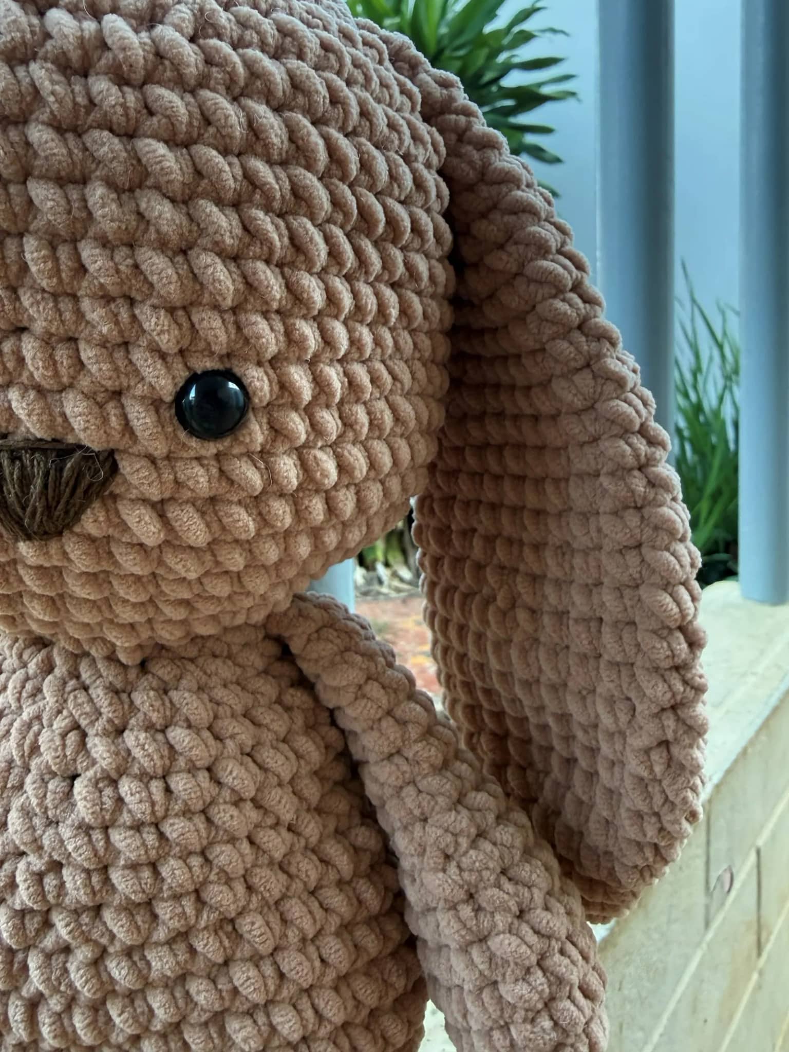 Rosto do coelho amigurumi de perto, com olhos de segurança e focinho bordado