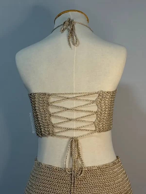 Costas do conjuntinho bege, com amarração em corset no top e saia de trama delicada