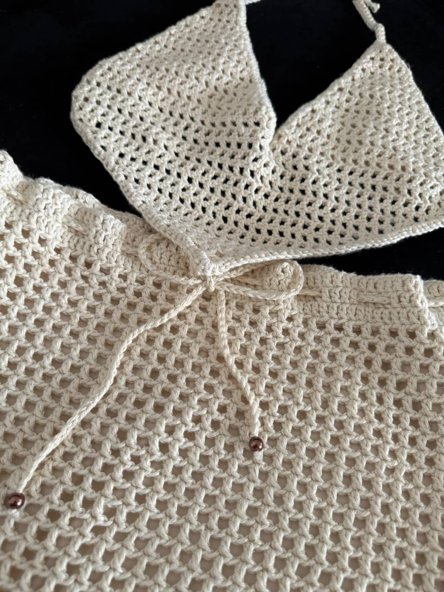 Detalhe da trama aberta da saia e do laço com pérolas, com o cropped ao fundo