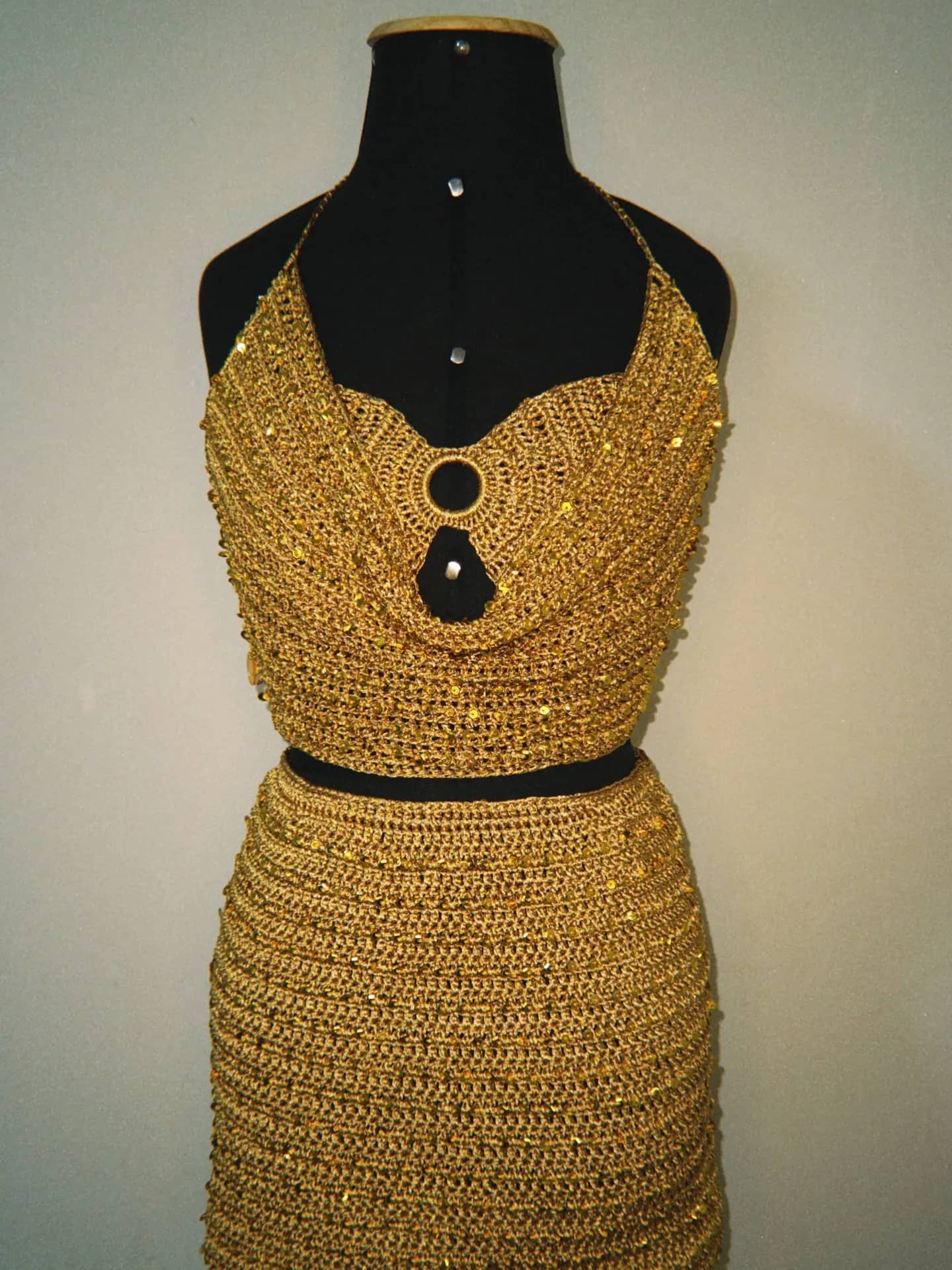 Conjunto de crochê dourado com brilhos, top com argola no decote e saia, no manequim