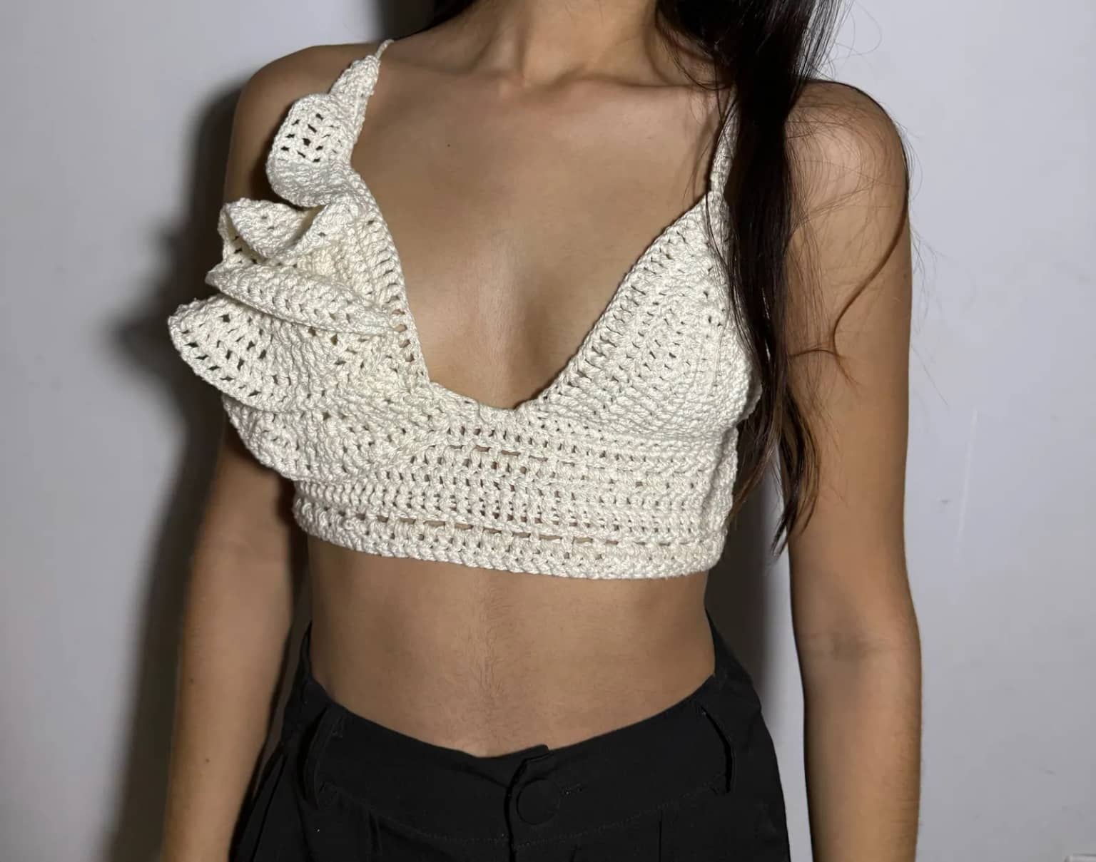 Cropped de crochê cru com babado em um ombro e alças finas, usado por cliente