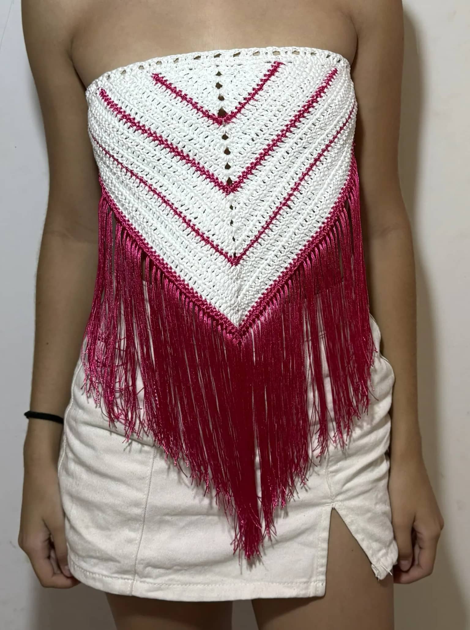 Cropped de crochê branco em triângulo invertido, com listras e franjas pink, usado por cliente