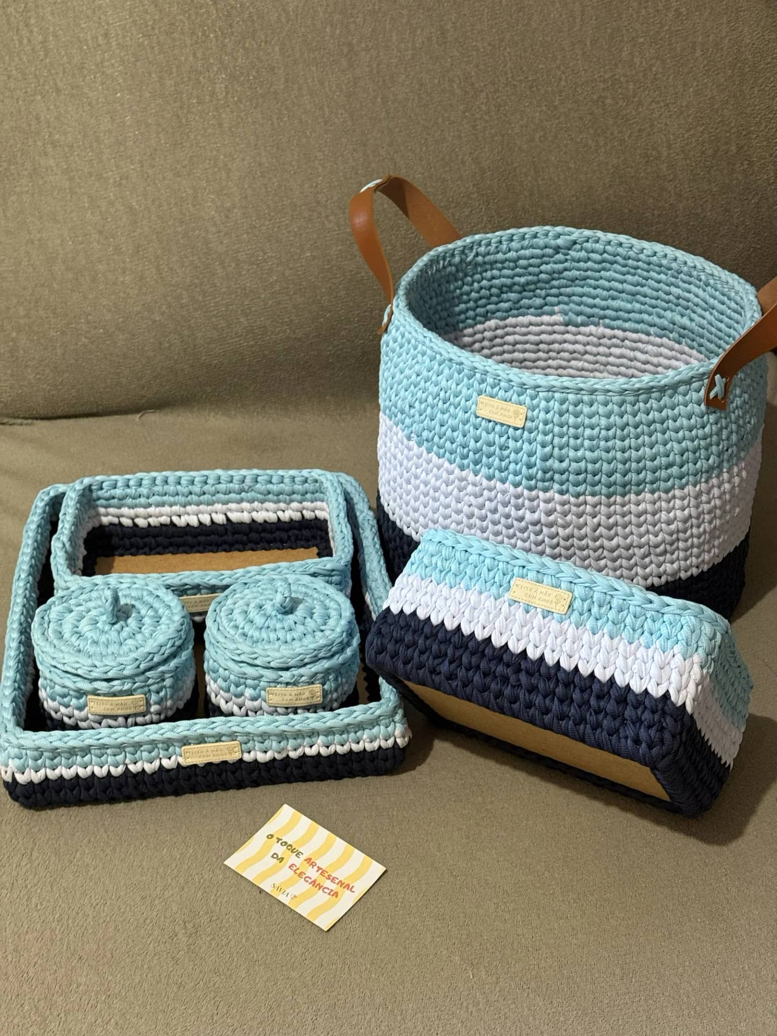 Kit de crochê azul, branco e azul-marinho: cesto com alças, caixa, bandejas e potes com tampa, sobre o sofá