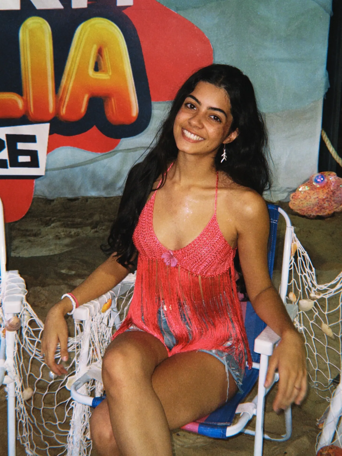 Cliente sorrindo usando cropped halter de crochê coral com franjas