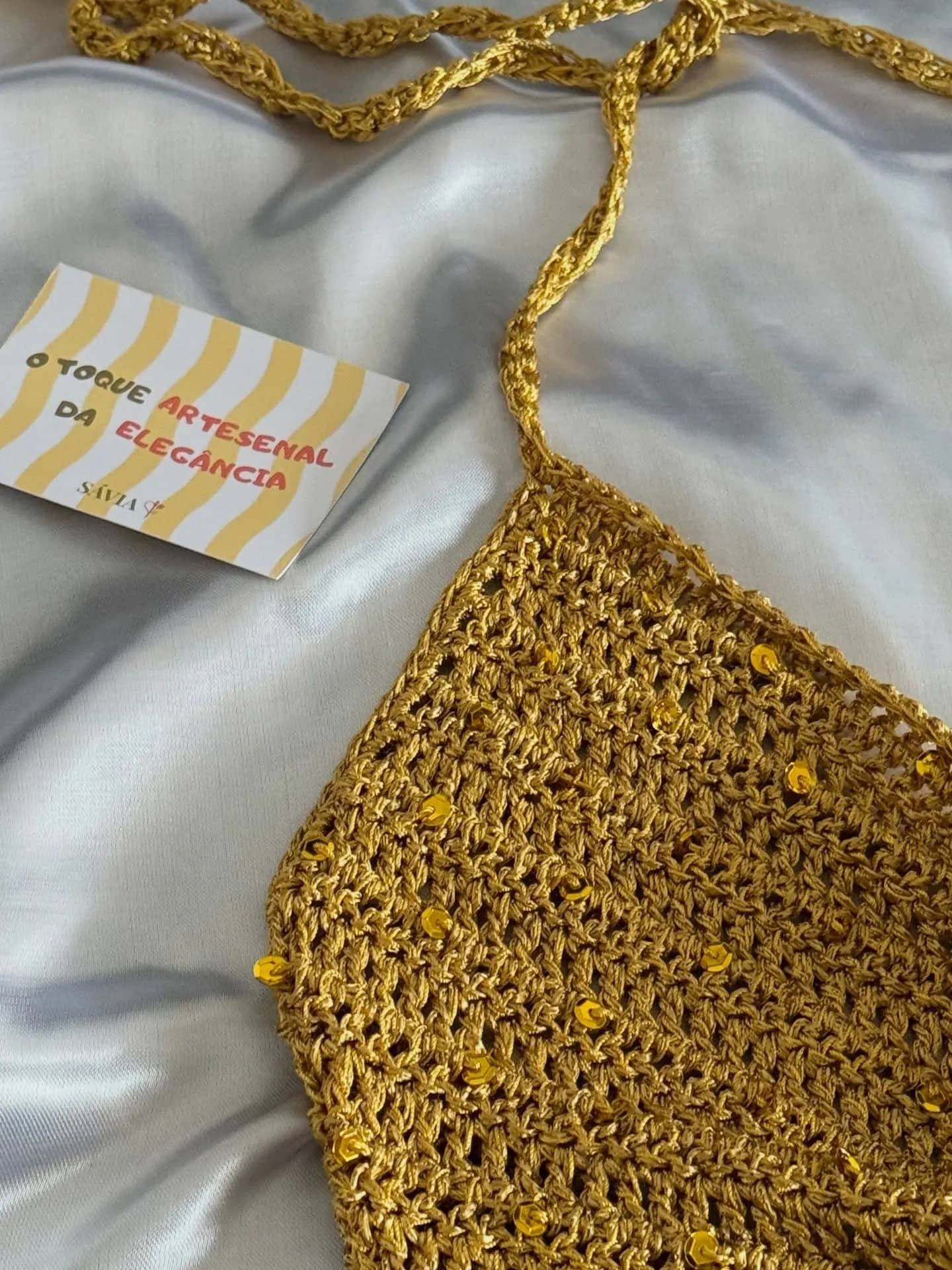 Detalhe do ponto dourado com o cartão O toque artesanal da elegância